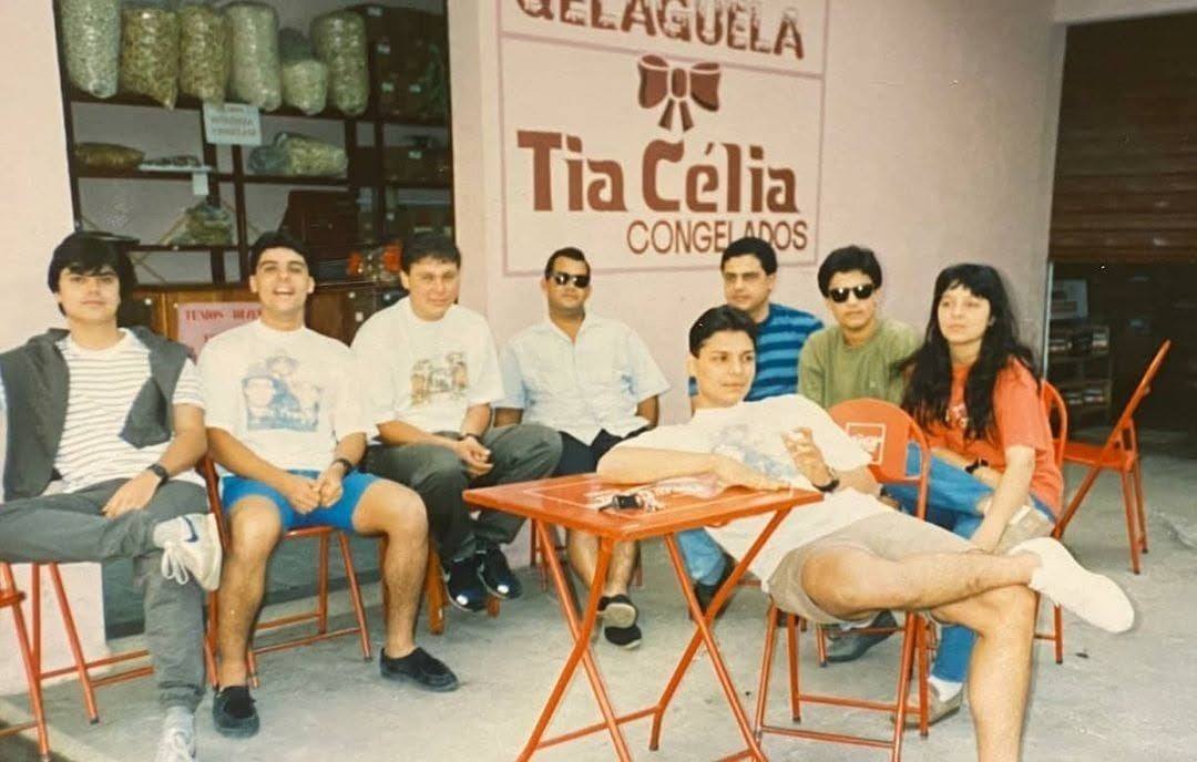 Grupo de clientes sentados às mesas na calçada, em frente à fachada antiga da sorveteria.