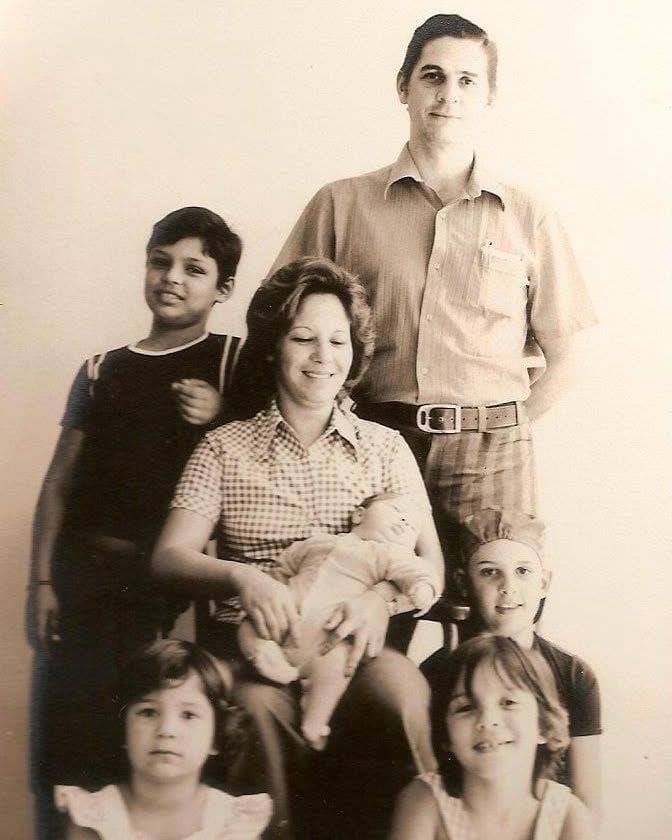 Fotografia antiga em tons sépia da Tia Célia com a família reunida.