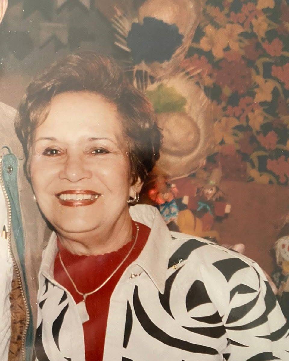 Retrato da Tia Célia sorrindo, de blusa vermelha e casaco estampado em preto e branco.