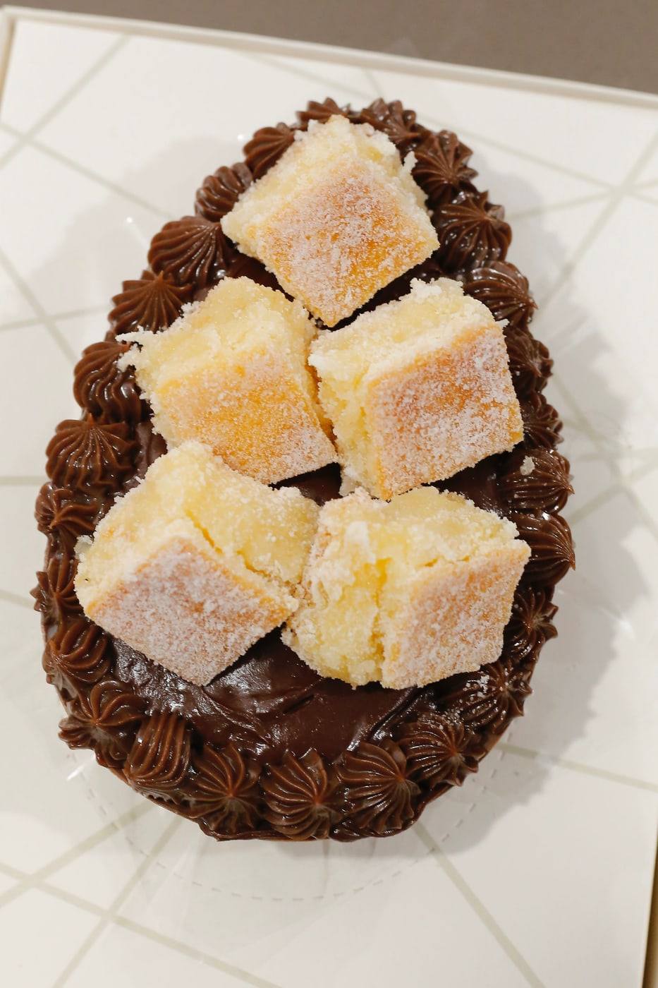 Meio ovo de Páscoa de chocolate recheado e decorado com rosetas de brigadeiro e cubos de doce.