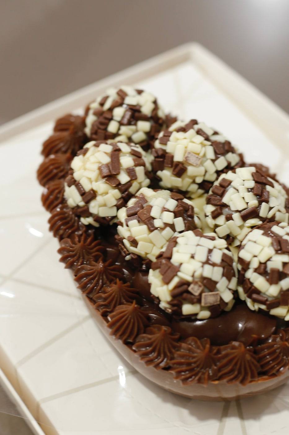 Meio ovo de Páscoa coberto de trufas confeitadas com chocolate branco e ao leite.