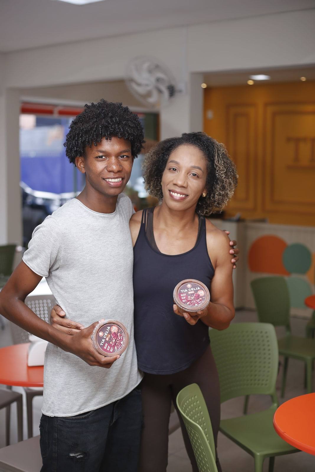 Mãe e filho sorridentes e abraçados no salão da Tia Célia.